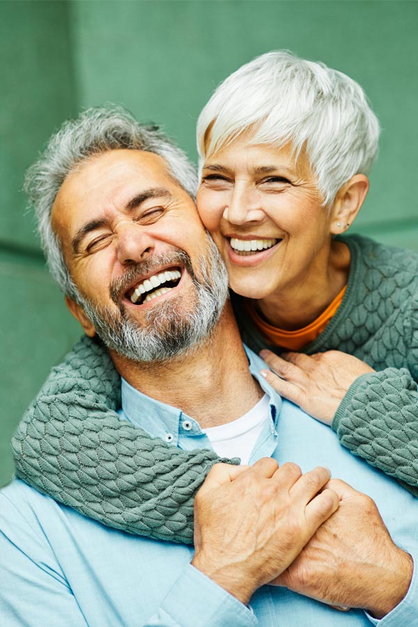 Bone-Marrow-Therapy-Treatment A healthy mature couple happily embrace on their porch. Get Bone Marrow Aspirate Concentrate Therapy for joint pain from Pierre Rojas, DO in South Lyon.