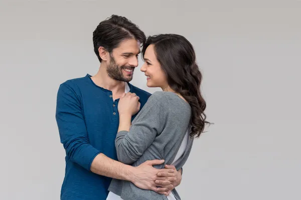 Erectile-Dysfunction-Doctor A man in a blue shirt embracing a woman in a gray shirt smiles due to his successful erectile dysfunction care from Pierre Rojas, DO in South Lyon.