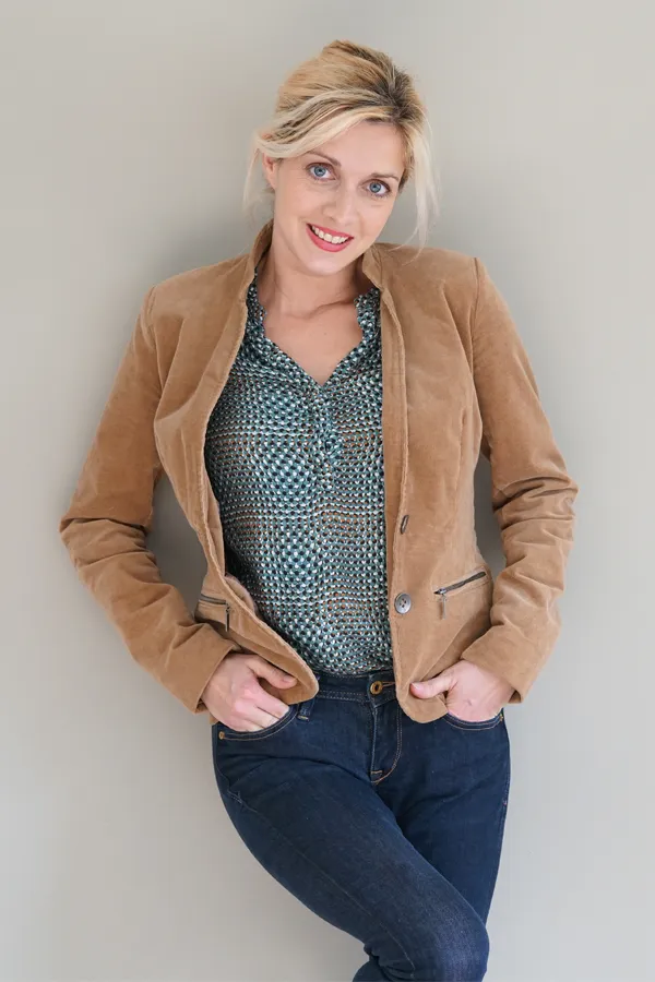 Metabolic-Syndrome-Treatment A smiling blonde woman in a tan leather jacket leans against a gray wall. Schedule metabolic syndrome from Pierre Rojas, DO in South Lyon.