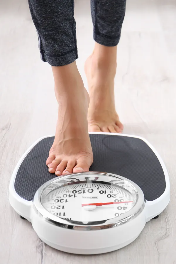 Obesity-Treatment Close up of feet stepping onto a scale. Receive expert functional medicine for obesity treatment by Pierre Rojas, DO in South Lyon.