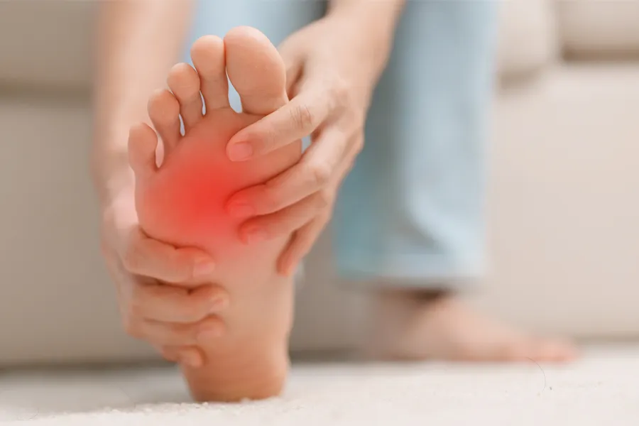 Plantar-Fasciitis-Clinic A woman holds her foot in pain. Schedule plantar fasciitis treatment from Pierre Rojas, DO in South Lyon.