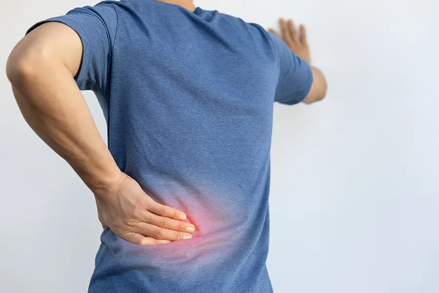 Sciatica-Clinic A man holds his lower back in pain. Schedule sciatica treatment from Pierre Rojas, DO in South Lyon.