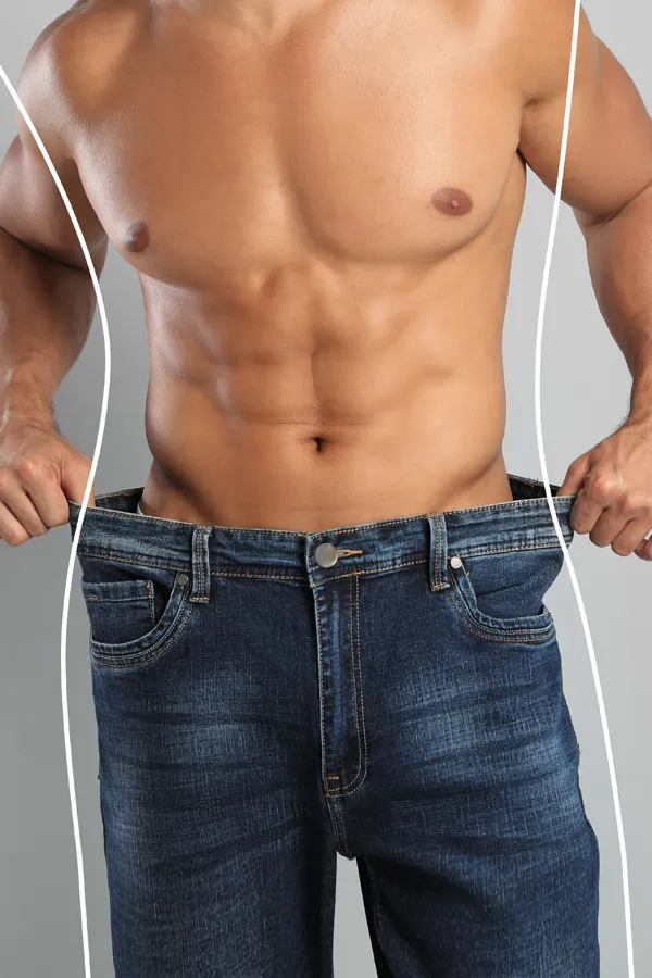 Semaglutide-Weight-Loss-Treatment A strong shirtless man in jeans holds the waistlines of his too-big jeans to show the success of semaglutide weight loss from Pierre Rojas, DO in South Lyon.